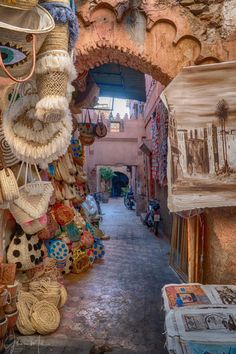 an alley way with baskets and hats hanging from the ceiling in front of a building