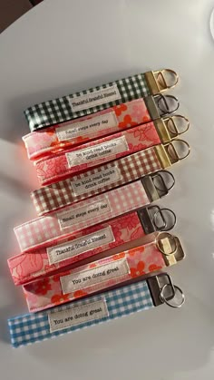 four key chains are lined up on a white plate with red and blue gingham designs