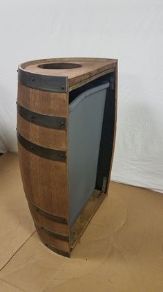 a wooden barrel with a tv inside of it sitting on the floor next to a white wall