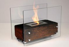 a wooden box with fire in it sitting on top of a white table next to a glass case