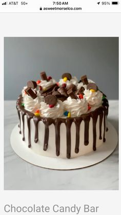 a white cake with chocolate icing and candy on the top that says chocolate candy bar