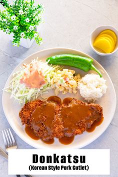 a white plate topped with meat covered in gravy next to rice and veggies