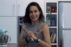 a woman holding two whisks in her hands