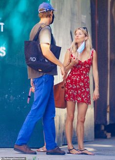 a man and woman standing on the sidewalk talking to each other while one holds his hand