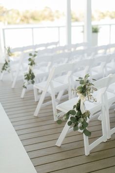 a row of white chairs sitting on top of a wooden floor