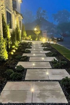 a long walkway with lights on each side in front of a house at night time