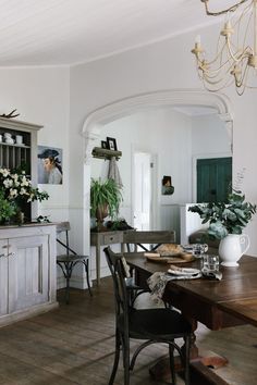 the dining room table is set for two with flowers in vases and plates on it