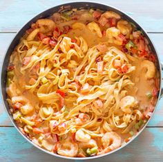 a pan filled with pasta and shrimp on top of a wooden table