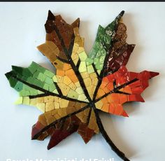 a multicolored maple leaf made out of broken tiles