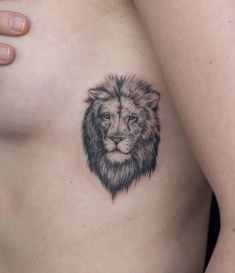 a woman's chest with a lion tattoo on her left side ribcage