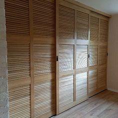 an empty room with wooden slats on the doors and hard wood flooring in it