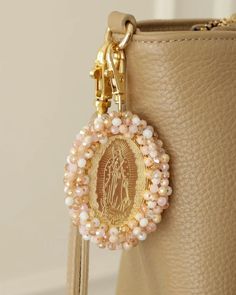 a small purse with a key chain hanging from it's front pocket and an image of the virgin mary