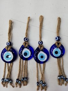 four evil eye glass beads hanging from twine with eyes painted on the front and back