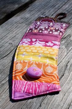 a purple and orange tie with a pink button on it's end sitting on a wooden surface