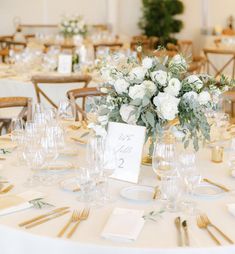 the table is set with white flowers and place settings for guests to sit down at