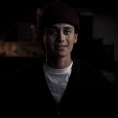 a young man wearing a hat in the dark