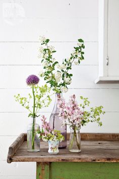 three vases filled with flowers sitting on top of a wooden table