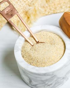 a white bowl filled with sand and two wooden utensils on top of it