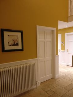 an empty room with yellow walls and white trim on the door, framed by a radiator