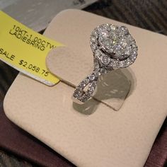 a diamond ring sitting on top of a white box with a price tag in front of it