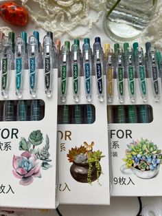 several pens are lined up next to each other on a table with succulents