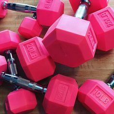 several pink dumbbells are laying on a wooden table with one barbell in the middle