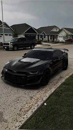 a black sports car parked in front of some houses