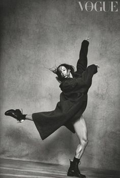 black and white photograph of a woman in an overstuffed coat dancing with her legs spread out