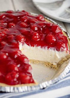 a cheesecake with cherries on top sits on a plate