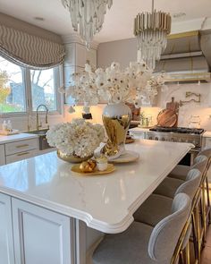 a white kitchen with gold accents and chandeliers