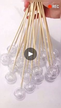 a hand holding a bunch of chopsticks with clear plastic balls in it and the video below