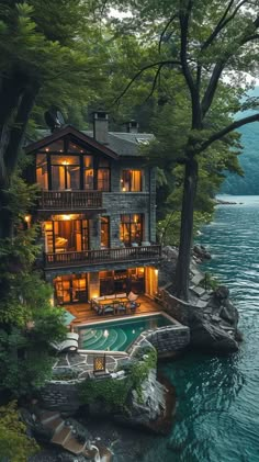 a large house sitting on top of a lush green hillside next to a body of water