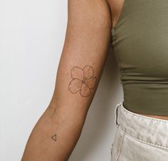 a woman's arm with a small flower tattoo on the left side of her arm