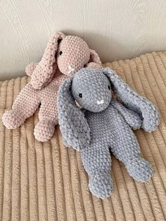 two crocheted stuffed animals sitting on top of a bed next to each other