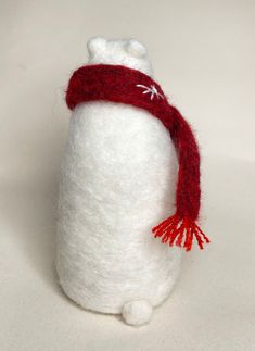 a white stuffed animal with a red scarf around it's neck