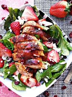 a salad with chicken, strawberries and feta cheese on top is served in a white bowl