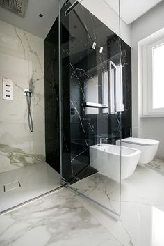 a black and white bathroom with two sinks, toilet and shower stall in the corner