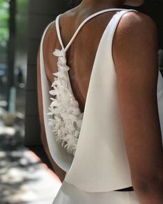 the back of a woman's dress with white flowers on it and an open neckline