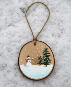 a wooden ornament with a snowman and trees on it