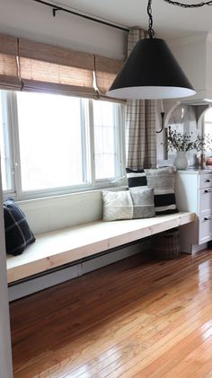 a large window seat in the middle of a room with wood floors and white walls