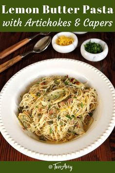 a white bowl filled with pasta next to two bowls of seasoning and spoons