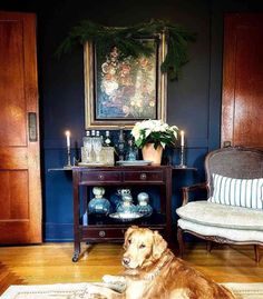 a large brown dog laying on top of a wooden floor next to a table with candles