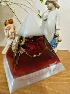 a vase with flowers in it sitting on a table next to a triangle shaped object