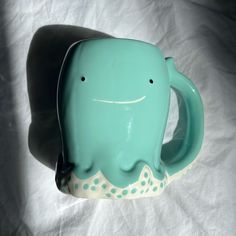 an elephant shaped coffee mug sitting on top of a white sheet