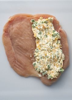 a piece of chicken with cheese and herbs on it