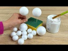 a person is painting white balls on a wooden table with green sponges and paint