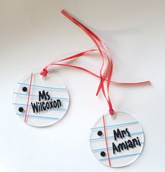 two personalized christmas ornament hanging from a red ribbon on a white surface