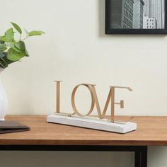 a wooden love sign sitting on top of a table next to a vase filled with flowers