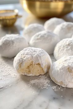 powdered sugar cookies are sitting on a marble counter top next to a gold bowl