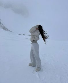 a woman standing on top of a snow covered slope